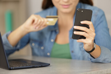 woman holding credit card and using smartphone