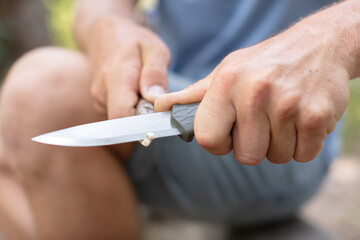young man with a knife cuts a wooden stick