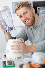 man sitting by desk repairing blender