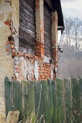 The missing part of the gutter pipe and the crumbling masonry behind a wooden lot.
