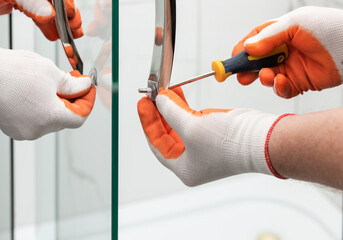Workers are mounting door handles of the shower enclosure.