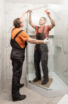 Workers Are Installing Glass Door Of The Shower Enclosure.