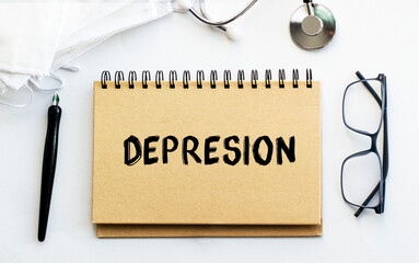 Inscription - DEPRESION. Written in a notepad to remind you of what's important. Top view of the table along with a stethoscope and a mask. Health care concept.