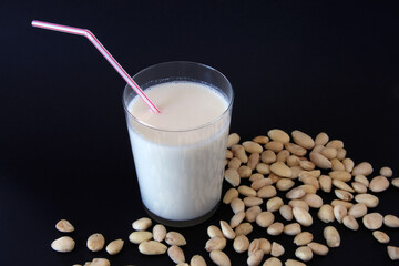 Vaso de leche de almendras, con varias almendras i fondo negro.