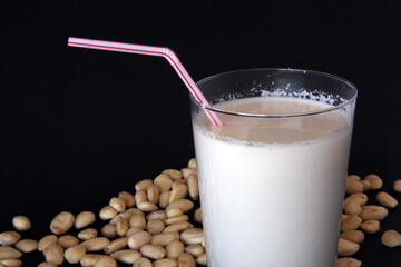 Vaso de leche de almendras, con varias almendras i fondo negro.
