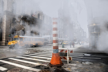 Steam heat pipe on New York city street construction work make fog and smoke