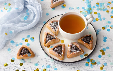 Homemade hamantashen cookies (Haman's ears) with poppy seeds and apples in a festive atmosphere with confetti on a light gray background. concept of celebration of Purim, jewish carnival
