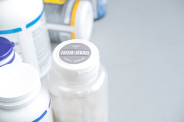 Jars with vegan supplements and vitamins for sports and health on a gray background, the inscription on the jar with non-gmo vitamins 100% vegan