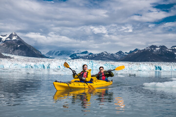 Happy couple enjoy kayaking near the glacier  and iceberg in Alaska - 415014291