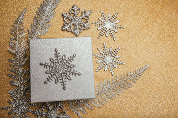 Christmas gift box and silver decorations on golden background.