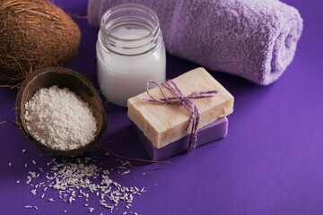 Organic coconut cosmetic oil and natural handmade soap with coconut on purple background