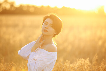 Fototapeta na wymiar girl in the rays of the setting sun in a wheat field