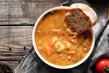 Red lentil soup and ingredients. Wooden background, top view. Traditional spicy soup made from lentils and vegetables. Healthy vegan food