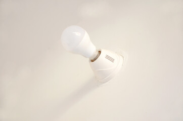 Closeup of a white bulb with holder attached on a white wall