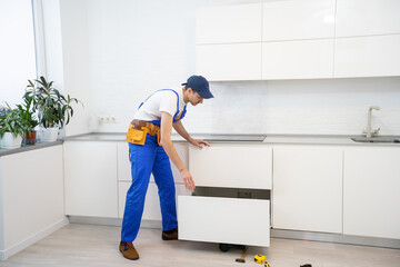 Young man assembling kitchen furniture.