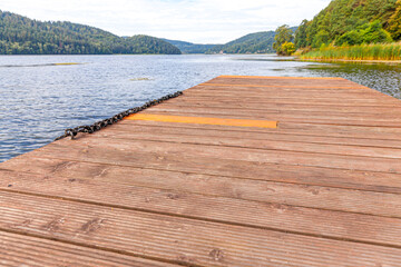 Fishing tourism relax concept. Beautiful forest lake or river on sunny summer day and old rustic wooden dock or pier. Fishing bridge on morning lake.