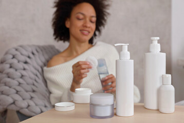 Woman applying lotion to cotton disc. Beauty routine at home. Selective focus on Skin care Products,copy space