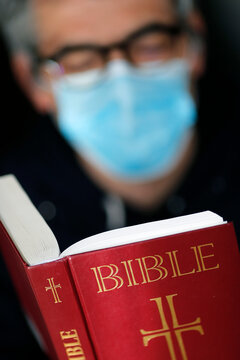 Man reading the bible with a disposable mask to avoid contagious coronavirus (COVID-19), France