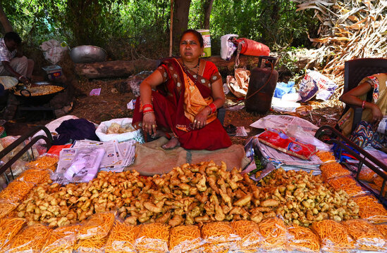 Adivasi woman selling freshly cooked pakora at traditional village fair celebrating Holi festival, Gujarat, India