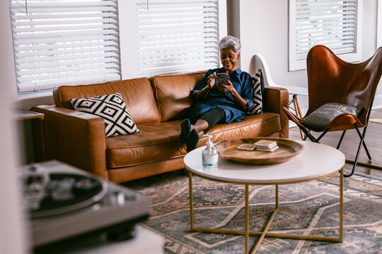 Black senior woman reading news on cellphone at home