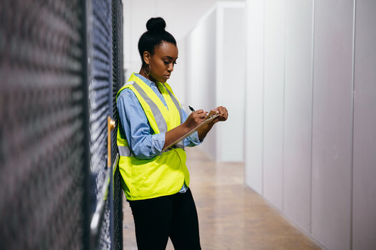 African American woman in datacenter surveying warehouse is secure