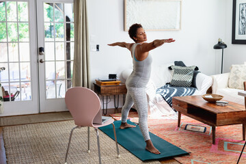 African American woman does yoga watching online tutorial on laptop computer