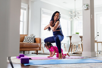 Toddler girl plays with mommy while she is exercising
