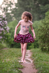 Barefoot girl walks through a puddles of water after the summer rain.