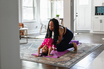 Black mom helps daughter practice yoga exercise together
