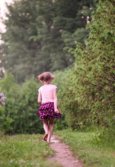 Barefoot girl walks through a puddles of water after the summer rain.