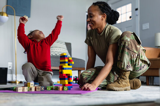 Black mother and daughter celebrating and having fun playing games in family room at home
