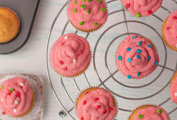 top view, vanilla muffins decorated with cream and sugar multicolored decor. stand in a circle....