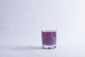 A glass of purple blueberry juice on grey background