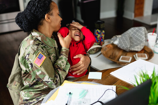 Daughter laughs and spends time with soldier mother working from home