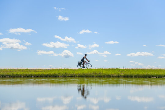 Cyclist riding past water, Ontario, Canada - Powered by Adobe