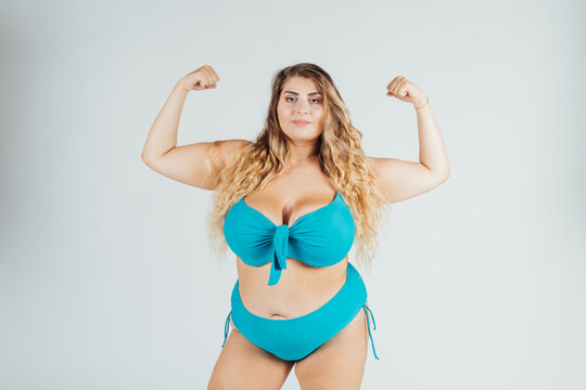 Young woman wearing bikini, flexing muscles