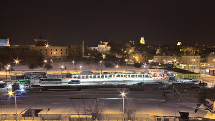 Snow-covered bus station against the backdrop of the night city