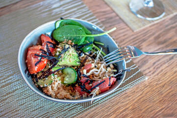 Healthy lunch bowl with tomato, cucumber avocado,quinoa, arugula fresh vegetables