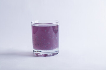 A glass of purple blueberry juice on grey background