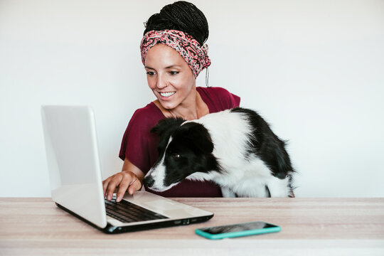 Female freelancer with Border Collie using laptop on table at home office