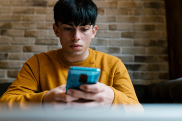 Young man using mobile phone while sitting at cafe