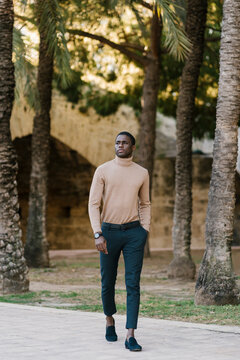 Young man with hands in pockets looking away while walking at park