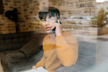 Man looking away while talking on mobile phone while sitting at cafe