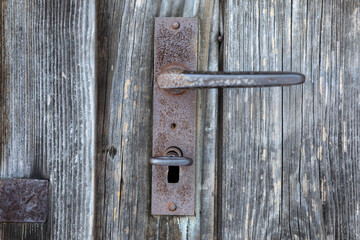Old wood door with key, door handle, and detail of rust and patina. 