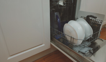 Open dishwasher with washed dishes in the kitchen.