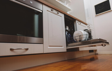 Open dishwasher with washed dishes in the kitchen.