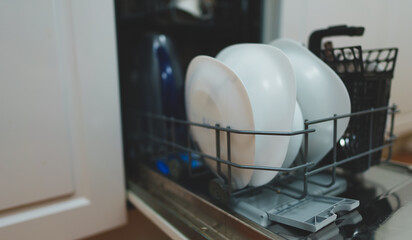 Open dishwasher with washed dishes in the kitchen.