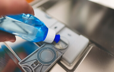 Man pours rinse aid into the dishwasher compartment.