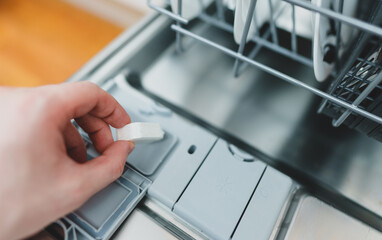 Man putting detergent tablet into dishwasher.