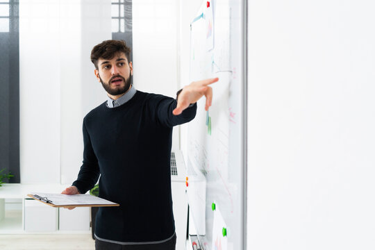 Businessman having presentation in office, pointing at whiteboard